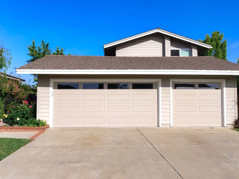 Three-car garage with cream sectional doors on a suburban home