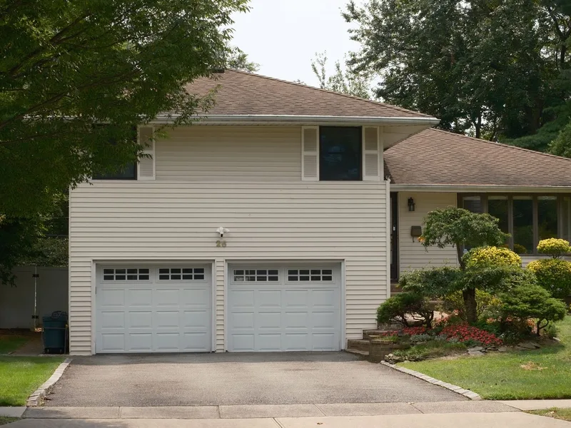 Two white sectional garage doors on a split-level home